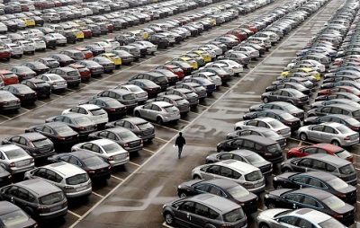 An employee walks past new cars at the parking lot of Changan Ford Mazda Automobile Co. Ltd, Ford Motor's joint venture in China, in Chongqing Municipality, October 12, 2010. Automakers in China shipped 19.3 percent more passenger cars to dealers in September from a year ago, official data showed, extending a rebound begun in August ahead of the peak auto sales season.