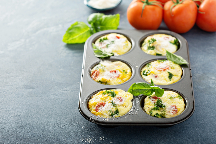 Healthy egg muffins, mini frittatas with tomatoes and greens topped with grated parmesan with copy space