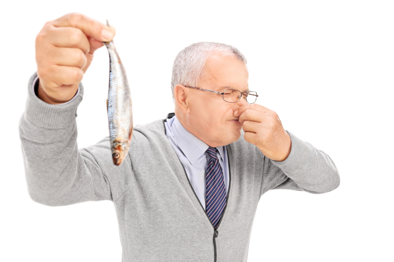 Senior gentleman holding a rotten fish isolated on white background