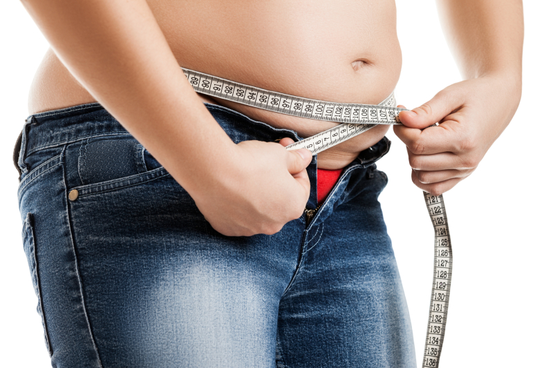 Overweight woman wearing jeans measuring her fat body belly paunch