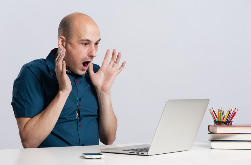 shocked bald man in horror looking at the laptop computer