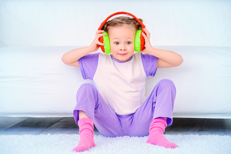 Cute little girl listens to music in headphones at home. Leisure. Family at home.