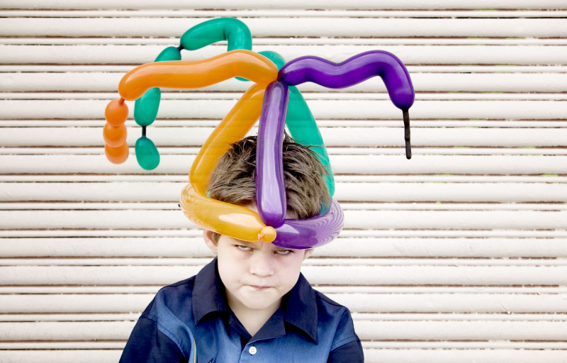 Young boy wearing a balloon hat with an angry face
