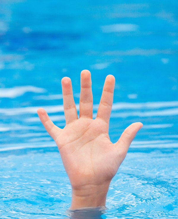A hand of a drowning person stretching out of the water in a swimming pool asking for help. Stress concept.