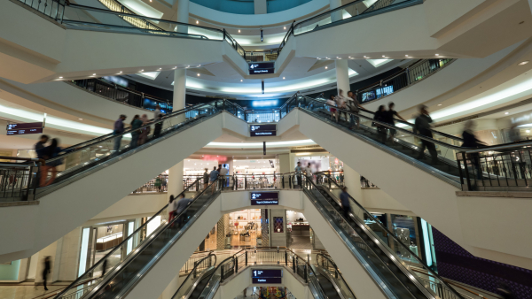 Big light multistorey shopping mall. Customers using escalators to get up and down. Trade centre of Petronas Twin Towers in Kuala Lumpur, Malaysia