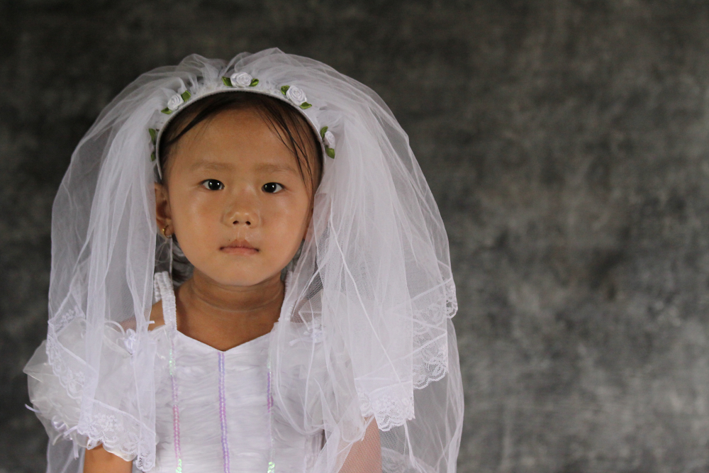 Portrait of Sumnima (5) from Nepal wearing white dress and veil.