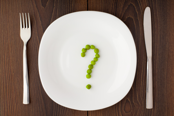 Question mark made of peas on a white plate