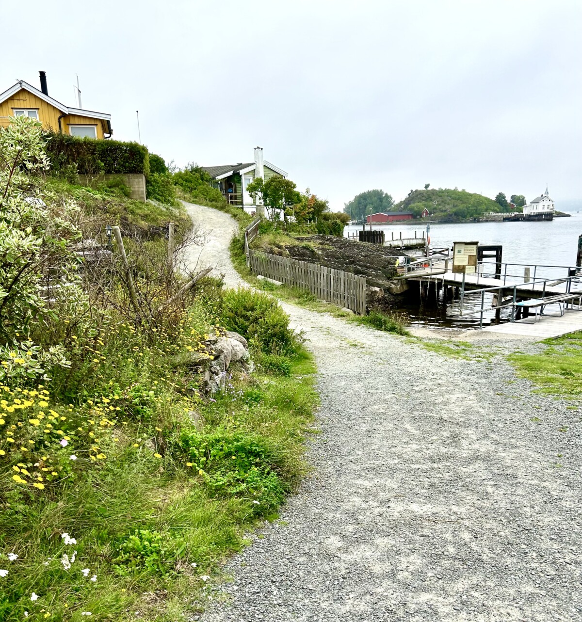 Idyllisk med gul hytte, vann og brygge på Lindøya i Oslofjorden