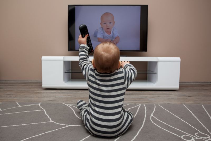 baby boy with remote controls watching television