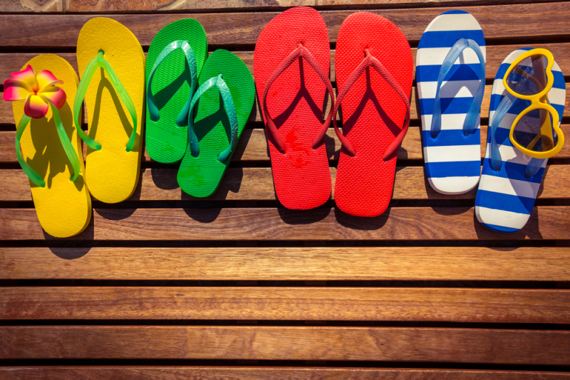 Multicolor flip-flops on wooden background. Summer family vacation concept