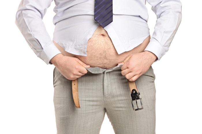 Overweight man trying to fasten too small clothes isolated on white background