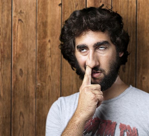 portrait of young man with the finger in his nose against a wooden wall