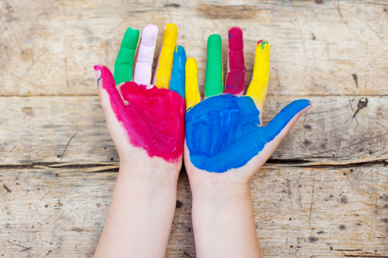 Colorful painted hands over the wooden background