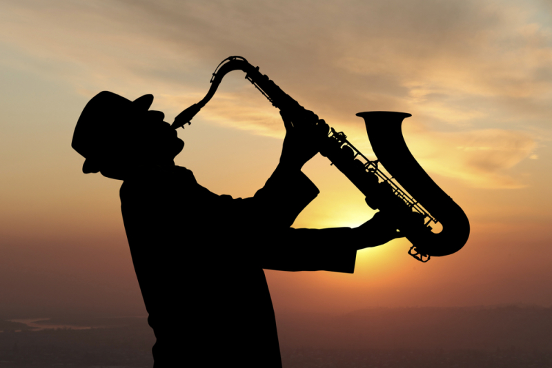 Saxophonist. Man playing on saxophone against the background of sunset