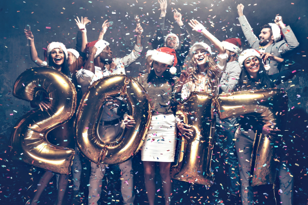 New Year is coming! Group of cheerful young people in Santa hats carrying gold colored numbers and throwing confetti 