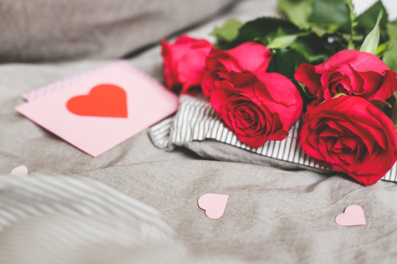 Romantic background with copy space. Beautiful roses and Valentine card with heart. Selective focus.